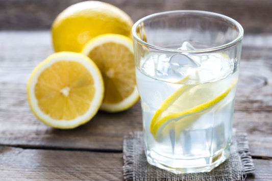 lemons on a table with a glass of iced lemon water