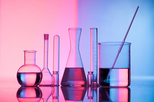 laboratory equipment including vials, conical flasks, test tubes, and a mixing pot filled with liquid set against a modern pink and blue background