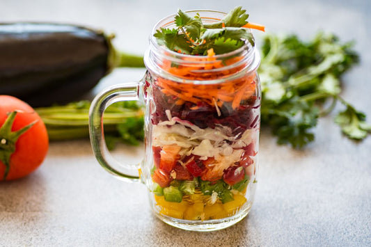 glass cup of layered vegetables, rainbow of vegetables, carrots, peppers, cabbage, coriander