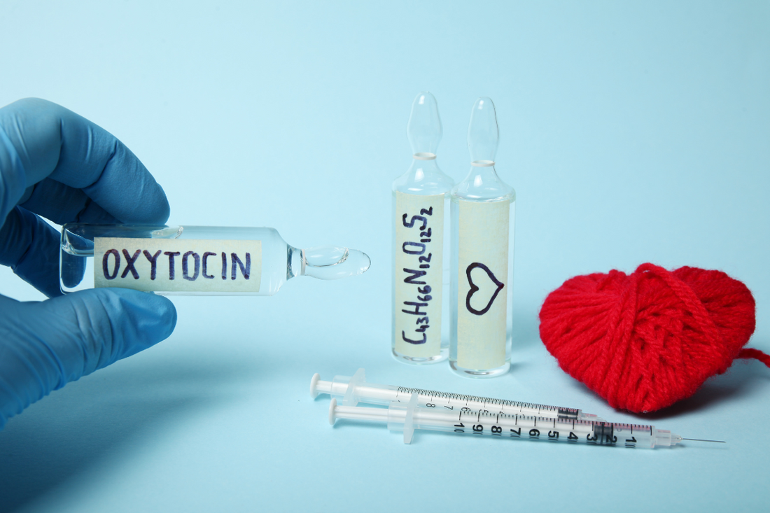 blue laboratory glove holding a glass tube of a hormone, with a blue background and a red heart made out of string