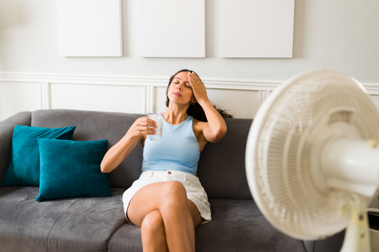 woman in a blue vest top with a white fan on her showing heatwave