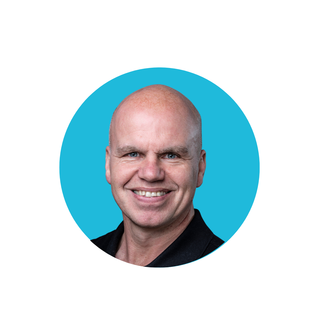 Steve Hackney, bald man with blue eyes and wearing a black top smiling at the camera, with a blue background