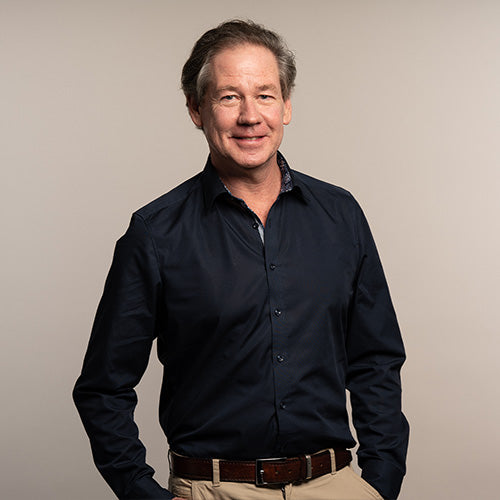 iüLabs Doctor Bob McDonald in a black suit and shirt, with a natural grey background