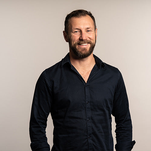 iüLabs Carlyle Jenkins talking and smiling, wearing a black shirt, with brown hair and a natural grey background