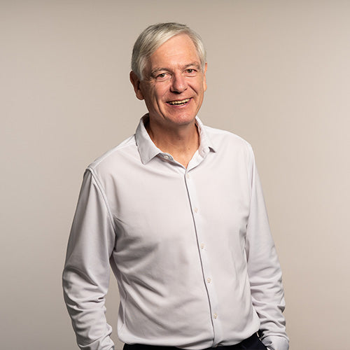 Doctor Wolfgang Brysch in a white shirt, smiling at the camera, with a nude grey background, scientist and founder at iüLabs